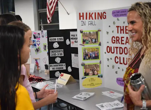 a club advisor explains her club to students at the club fair